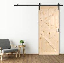 Load image into Gallery viewer, Wooden sliding barn door in a room with a chair and small table.