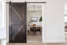 Load image into Gallery viewer, Dark wooden sliding barn door in a modern interior setting
