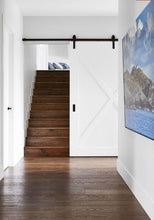 Load image into Gallery viewer, Staircase with a sliding barn door in a modern interior setting.
